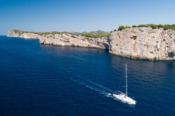 Yacht sailing on the Adriatic sea, cliffs of National park Telascica in background, Croatia