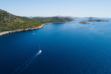 Yacht sailing on the Adriatic sea, cliffs of National park Telascica in background, Croatia