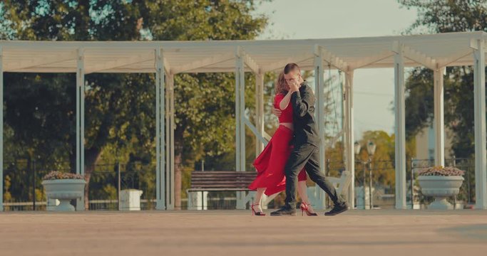 Dance steps and tango movements. Beautiful girl and elegant guy are dancing on the street in summer.