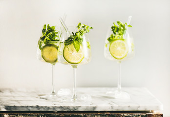 Hugo Sparkling wine cocktail with fresh mint and lime in glasses with eco-friendly straws over white marble counter, selective focus. Cold refreshing summer alcoholic drink - obrazy, fototapety, plakaty