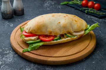 ciabatta with chicken on the board on dark grey concrete table