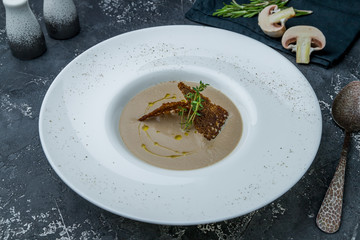 Cream soup of mushrooms on dark grey concrete table