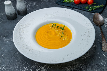 Soup cream of pumpkin on dark grey concrete table
