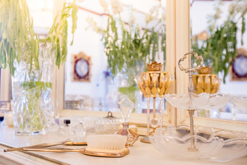 Beautiful vanity with purple flower petals and perfume bottles.Cosmetic set on light dressing table.soft focus.