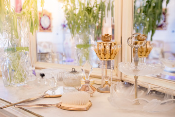 Beautiful vanity with purple flower petals and perfume bottles.Cosmetic set on light dressing table.soft focus.