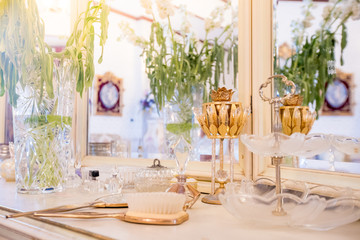 Beautiful vanity with purple flower petals and perfume bottles.Cosmetic set on light dressing table.soft focus.