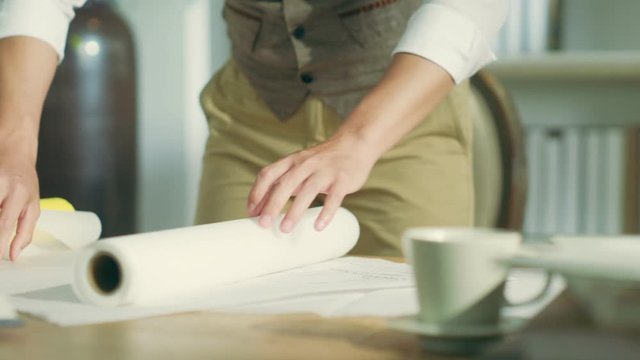 young architect or designer unfolding a roll of drafting paper