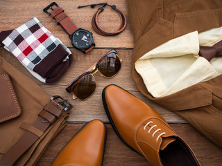 Men fashion casual clothing set and accessories on wooden background include oxford mustard shoes, yellow suit, pants, belt, sunglasses, sock, wallet , bracelet and office shirt. Flat lay, top view