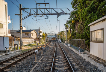 Bright clear blue sky in urban Japan with train tracks leading to a train station in the center of...