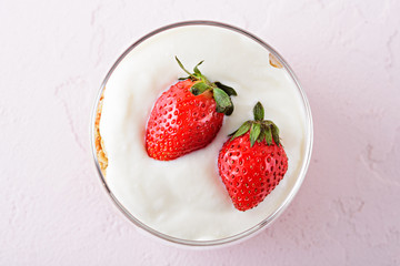 whipped cream with strawberries in glass on pink background