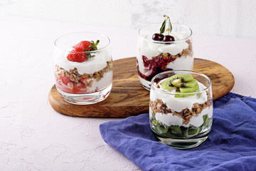 delicious and healthy desserts with ricotta cheese, granola, strawberries, cherries and kiwi on light pink background
