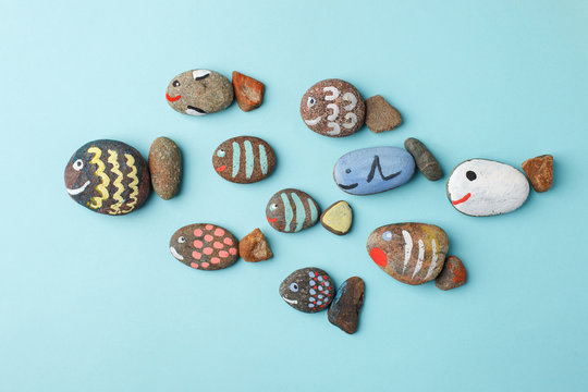 Multicolored stones and creative fish made of stone. The painting is painted in different colors in texture style on blue, DIY, kindergarten, daycare creative art, hobby