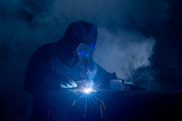 Professional welder and mask welding metal pipe on the industrial table.A welder is a tradesperson...