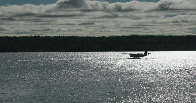 Silhouette of float plane on sparkling lake preparing for takeoff.