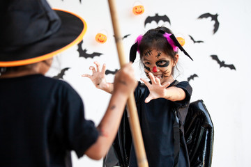 Two cute asian child girls wearing halloween costumes and makeup having fun on Halloween celebration together