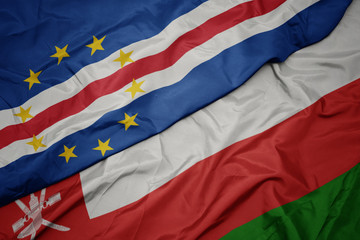 waving colorful flag of oman and national flag of cape verde.
