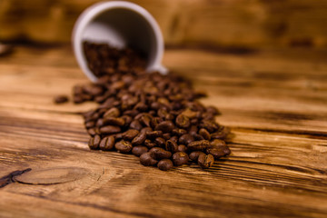 White cup and scattered coffee beans on wooden table