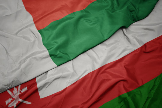 waving colorful flag of oman and national flag of madagascar.