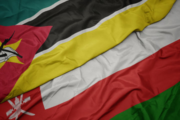 waving colorful flag of oman and national flag of mozambique.