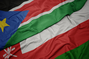 waving colorful flag of oman and national flag of south sudan.