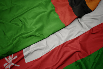 waving colorful flag of oman and national flag of zambia.