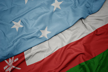 waving colorful flag of oman and national flag of Federated States of Micronesia .