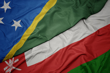 waving colorful flag of oman and national flag of Solomon Islands .