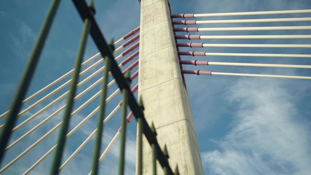 Concrete suspension cable bridge through rusty fences with cloudy sky at sunrise