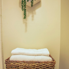 Square frame Folded towels inside a rattan bathroom tray placed on top of the toilet tank