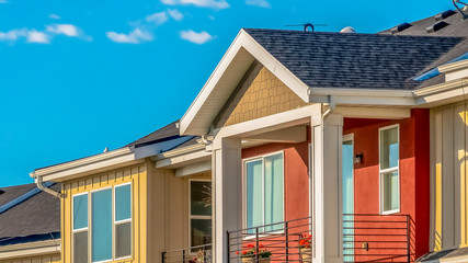 Panorama Exterior of townhomes with cream and red walls viewed against sky on a sunny day