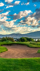 Vertical frame Hole filled with sand amid a grassy terrain against home lake mountain and sky