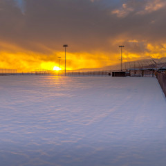 Square frame Stunning winter scenery with a golden sun setting against the sky filled clouds