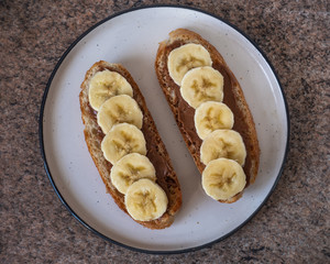 Two peanut butter and banana sandwiches, a healthy snack on a round plate, close-up