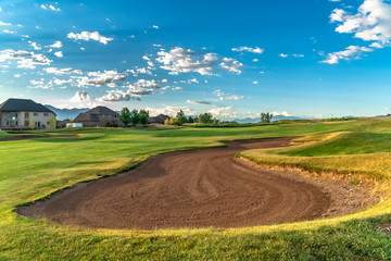 Fairway and bunker on a golf course with homes and mountain in the distance