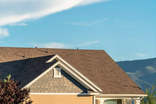 Close up of the roof of a home against blue sky and mountain on a sunny day