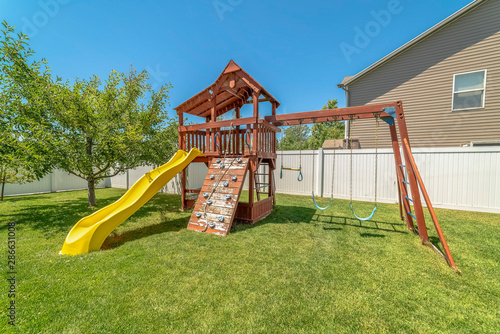 Wooden Playground Structure With Yellow Plastic Slide Swings And