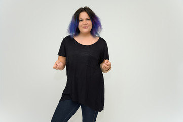 Stock Foto Portrait of a knee-deep funny cheerful girl of a young woman with multi-colored hair in a black T-shirt on a white background. In the studio, smiling, talking.