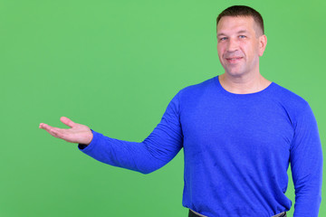 Portrait of happy macho mature man showing something
