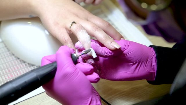 Professional manicurist cares for young woman's nails