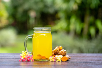 Energy tonic drink with turmeric, ginger, lemon and honey in glass mug, nature background, close up