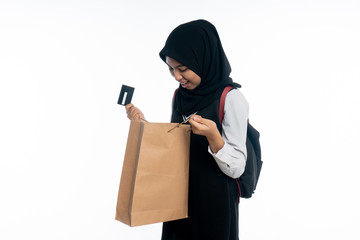 Happy Asian woman holding a card while looking inside the shopping bags