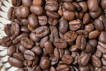 Coffee beans on a plate placed on a wooden table.