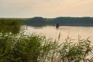Fototapeta na wymiar An elderly people fishing in boat around forest