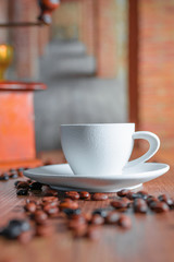 White porcelain cup and roasted coffee beans on a wooden table. Relaxation concept and coffee aroma.