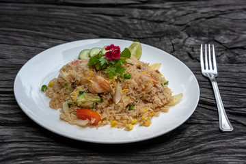 Fried rice with shrimps and vegetables in a white dish on an old wooden table, close up . Thai food , Thai cuisine