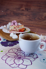 Fototapeta na wymiar flying food tea drinking donut in the air on a wooden background with colored sprinkling cake cheesecake with fresh berries strawberries