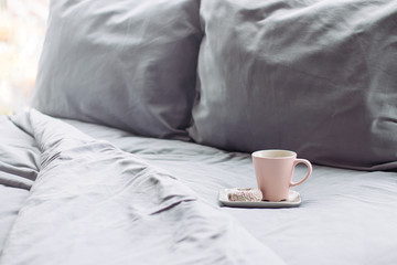 cup with coffee on grey bed. Pillow and blanket