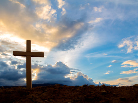 Silhouettes of crucifix symbol with bright sunbeam on the colorful sky background