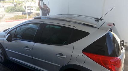 A man in a car wash, washes a dirty car.