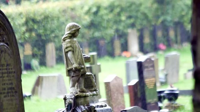 Angel girl stone grave headstone in rainy cemetery. Sad, mourning, sorrow remembrance figure.